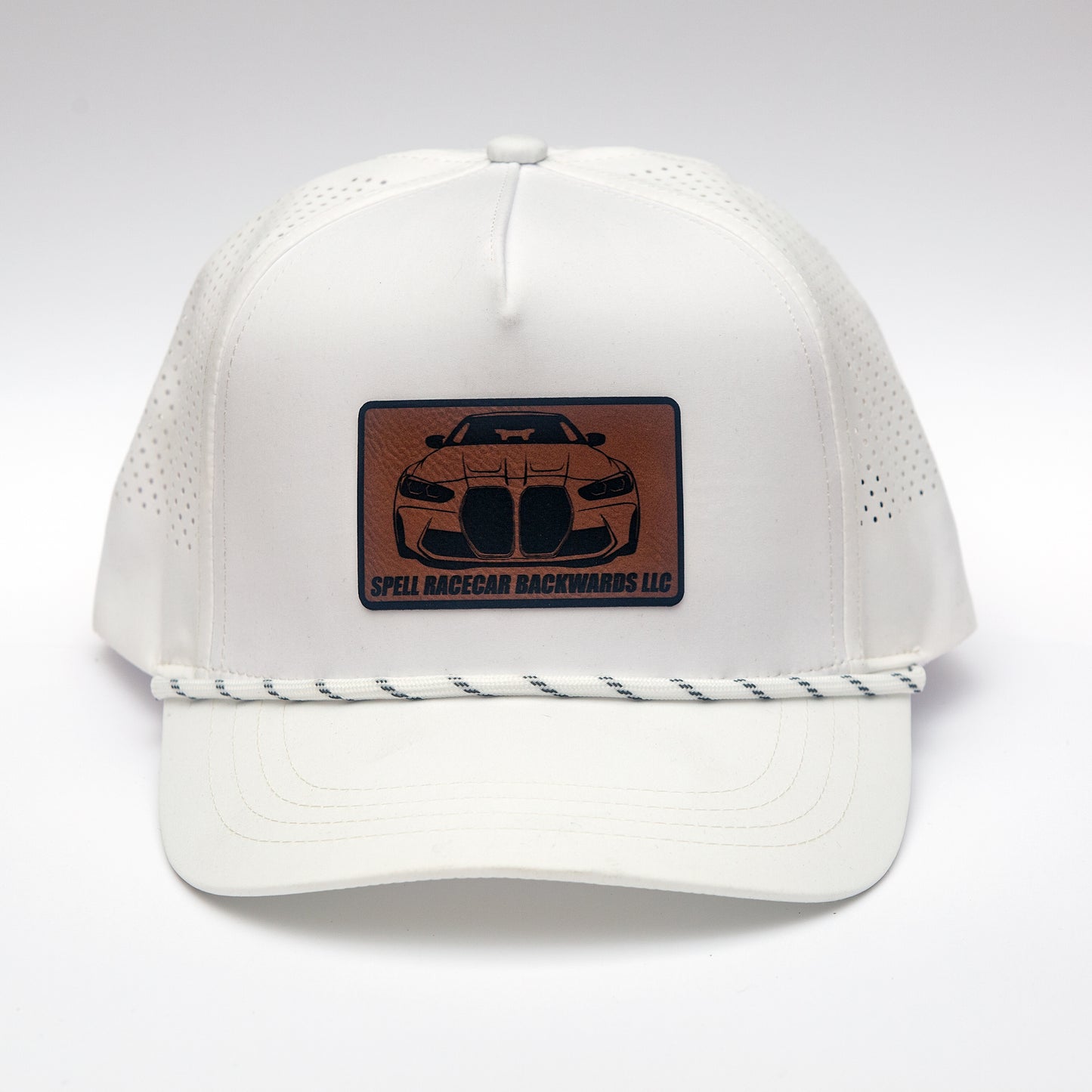 front view of white ball cap with leather patch with front view illustration of car, photographed on white background