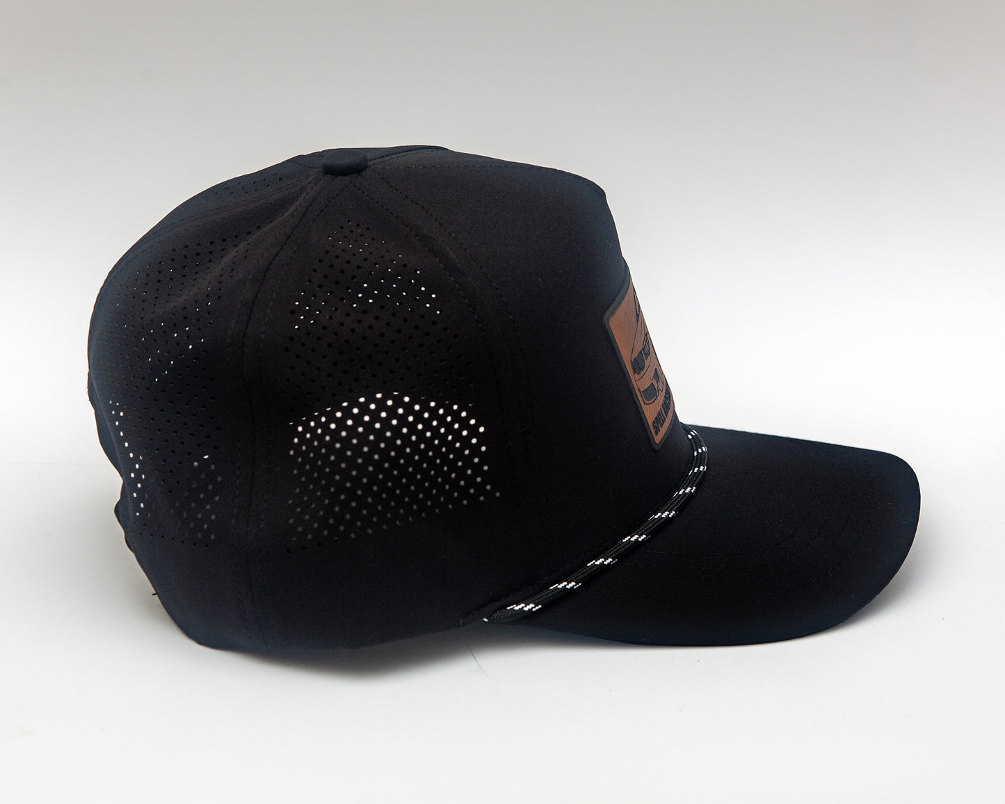 side view of black ball cap with leather patch with illustration of car, photographed on white background