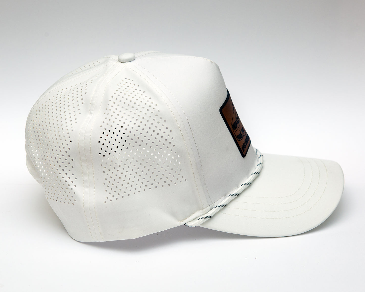 side view of black ball cap with leather patch with illustration of car, photographed on white background