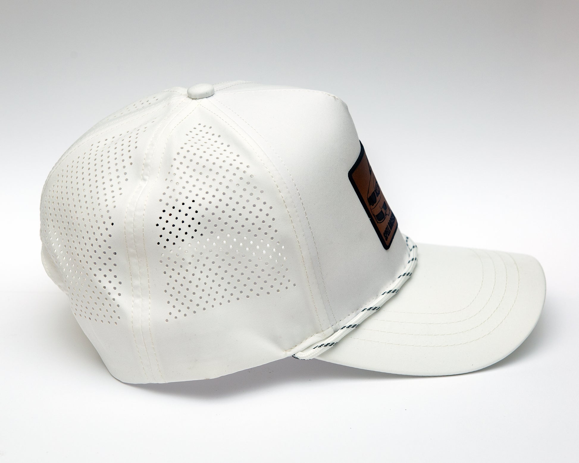 side view of black ball cap with leather patch with illustration of car, photographed on white background