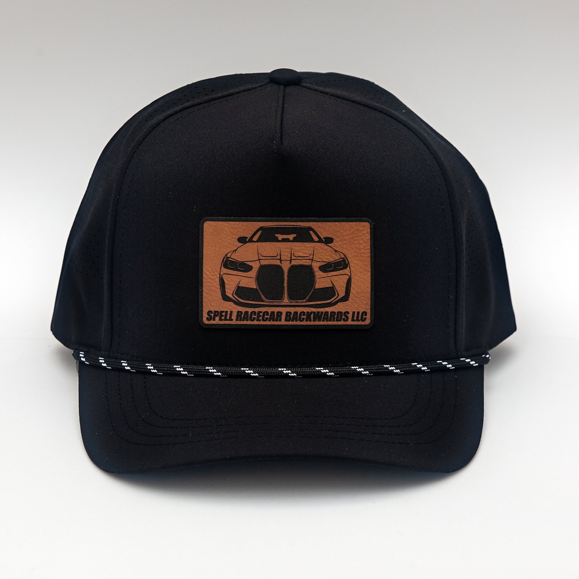 front view of black ball cap with leather patch with front view illustration of car, photographed on white background