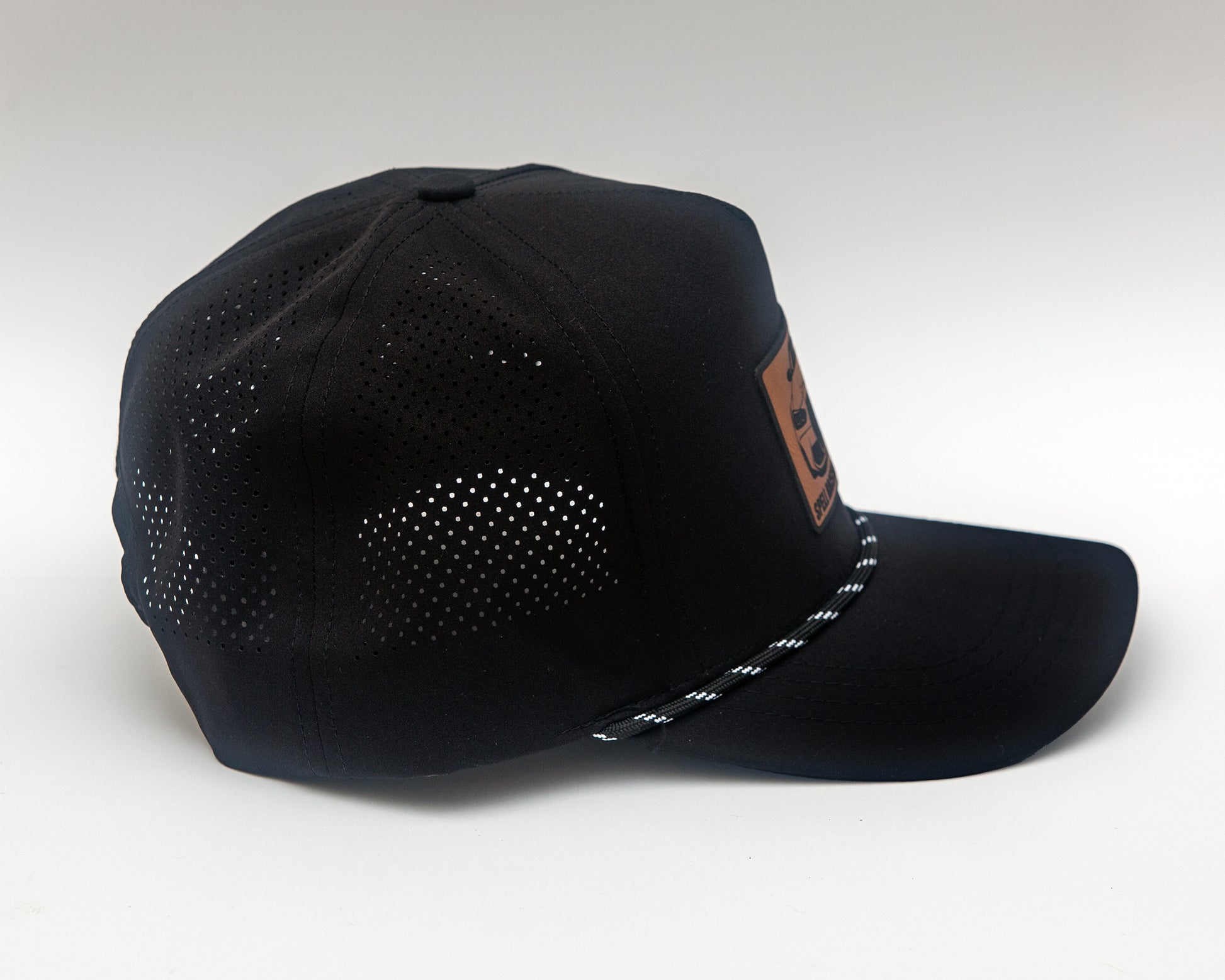 side view of black ball cap with leather patch with front view illustration of car, photographed on white background